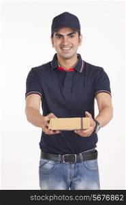 Portrait of confident delivery man giving package against white background