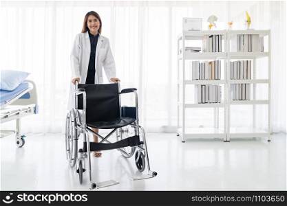 Portrait of confident female doctor medical professional holding wheelchair examination room in hospital clinic