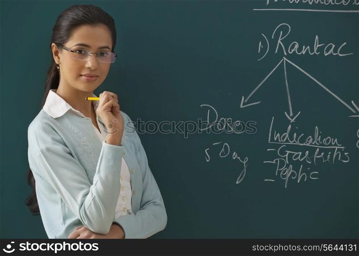 Portrait of confident female teacher against green board