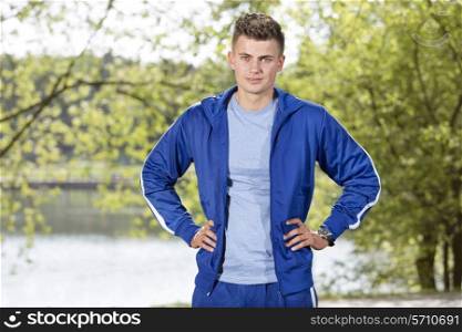 Portrait of confident fit man standing with hands on hips in park