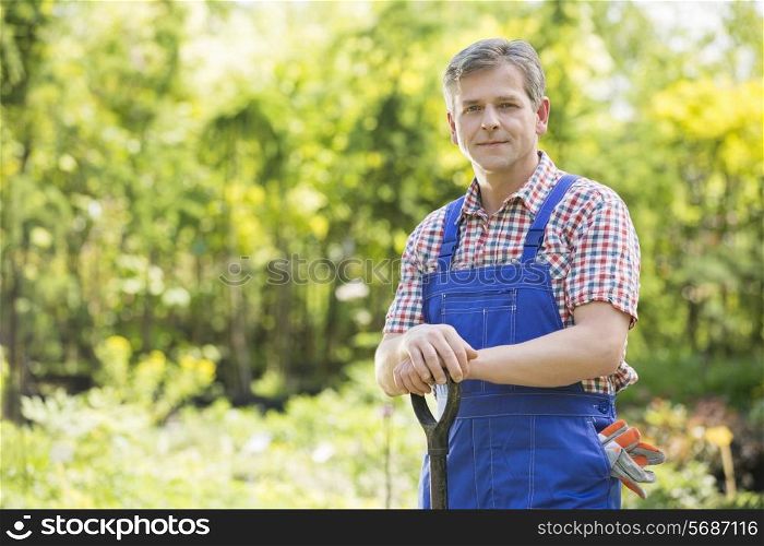 Portrait of confident gardener holding spade in plant nursery