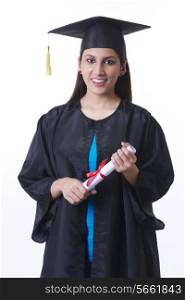 Portrait of confident graduate student holding diploma against white background