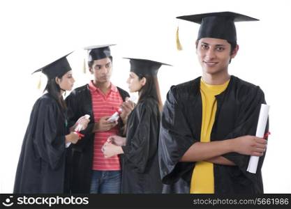 Portrait of confident graduate student with friends discussing against white background