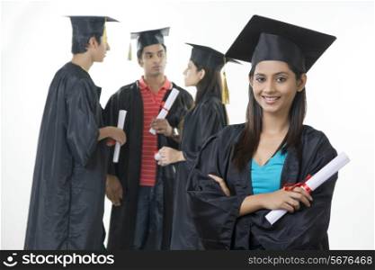 Portrait of confident graduate student with friends discussing over white background