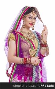 Portrait of confident Indian bride smiling against white background