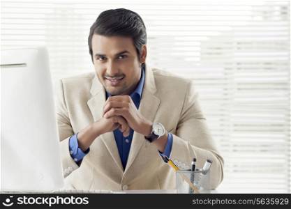 Portrait of confident Indian businessman sitting at computer desk