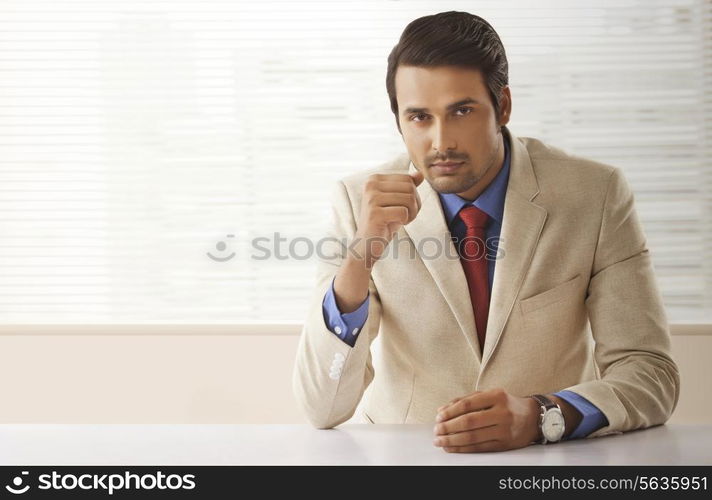 Portrait of confident Indian businessman sitting at office desk