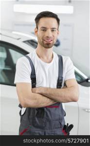 Portrait of confident maintenance engineer standing arms crossed in repair shop