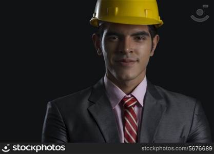 Portrait of confident male architect wearing hardhat against black background