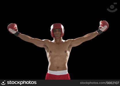 Portrait of confident male boxer standing with arms outstretched over black background