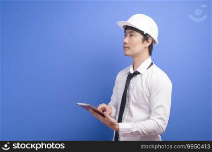 Portrait of confident male engineer wearing a white using tablet over blue  background studio