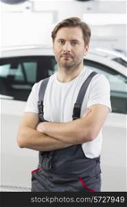Portrait of confident male mechanic standing arms crossed in workshop