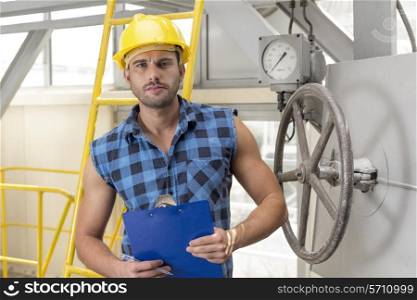 Portrait of confident male worker holding clipboard in industry