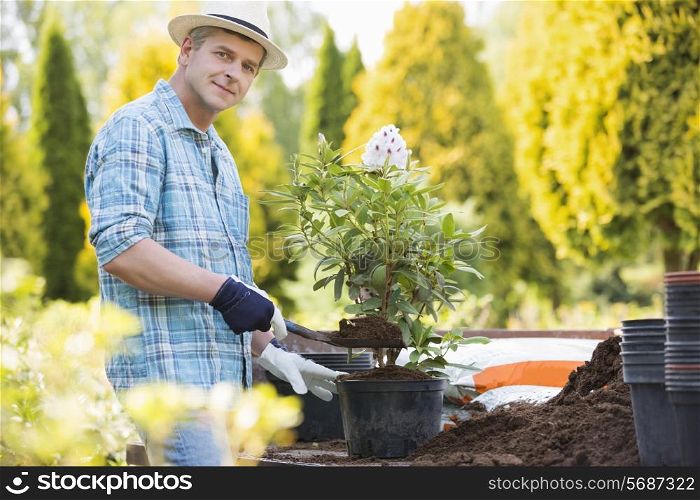 Portrait of confident man planting pot at garden