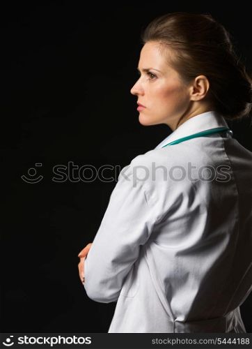 Portrait of confident medical doctor woman looking on copy space isolated on black