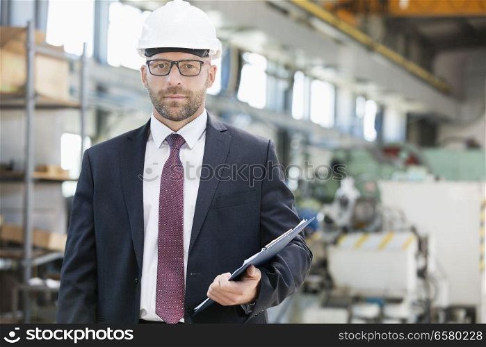 Portrait of confident mid adult male supervisor holding clipboard in metal industry