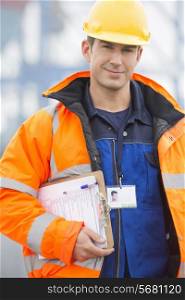 Portrait of confident mid adult man with clipboard in shipping yard