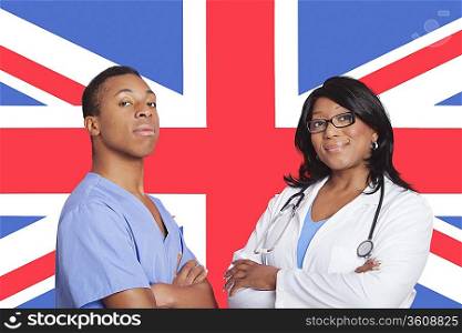 Portrait of confident mixed race male and female surgeons over British flag