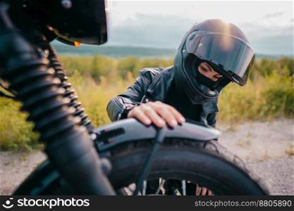 Portrait of confident motorcyclist woman in helmet sitting near bike. Young driver biker outdoors at sunset. High quality photo. Portrait of confident motorcyclist woman in helmet sitting near bike. Young driver biker outdoors at sunset.