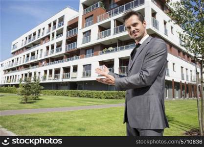 Portrait of confident real estate agent showing office building