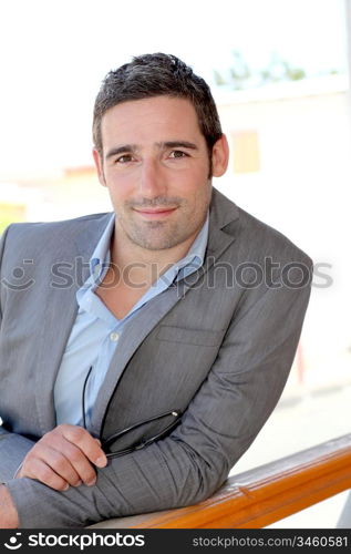 Portrait of confident salesman leaning on balustrade