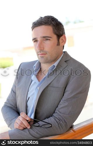 Portrait of confident salesman leaning on balustrade