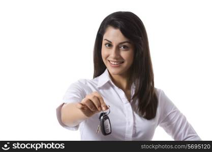 Portrait of confident saleswoman holding car keys against white background