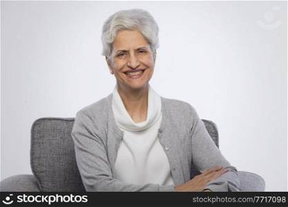 Portrait of confident senior woman sitting on sofa