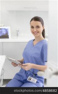 Portrait of confident smiling nurse with clipboard at dental clinic