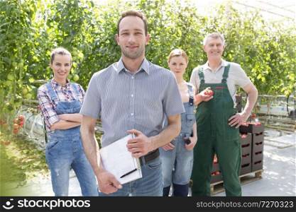 Portrait of confident supervisor and gardeners standing at greenhouse