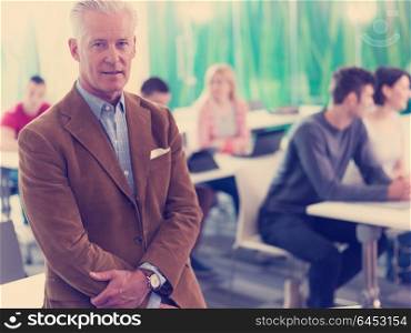 portrait of confident teacher in school classroom, students group on class in background