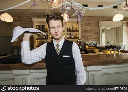 Portrait of confident waiter carrying serving tray in restaurant