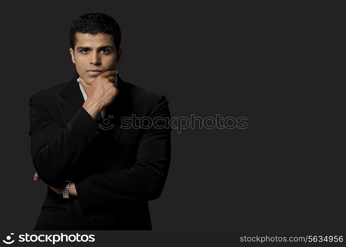 Portrait of confident young business man over black background