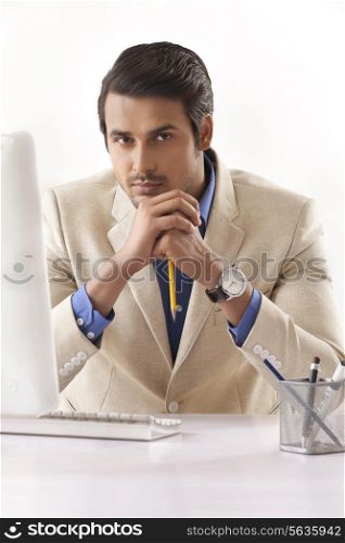 Portrait of confident young businessman at computer desk