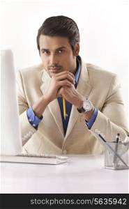 Portrait of confident young businessman at computer desk