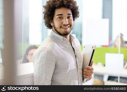 Portrait of confident young businessman holding laptop in office