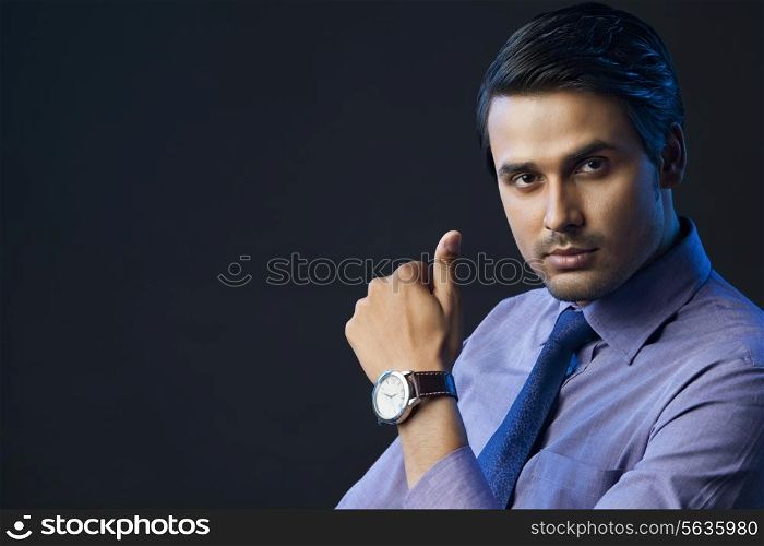 Portrait of confident young businessman over black background