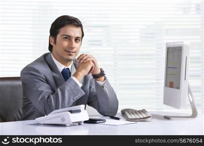 Portrait of confident young businessman sitting at office desk