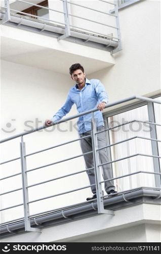 Portrait of confident young businessman standing at hotel balcony