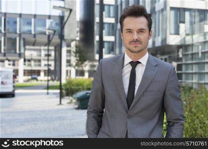 Portrait of confident young businessman standing outside office building