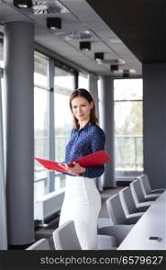 Portrait of confident young businesswoman holding file in conference room