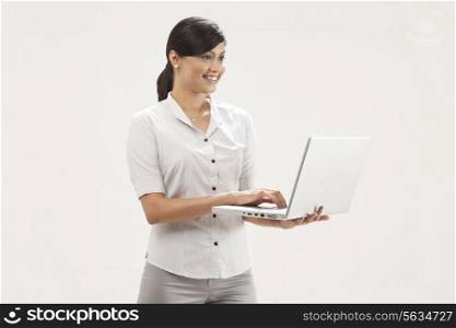 Portrait of confident young businesswoman holding laptop