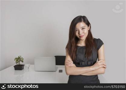 Portrait of confident young businesswoman standing arms crossed in office