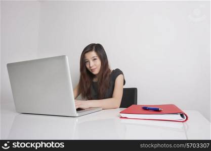 Portrait of confident young businesswoman using laptop in office
