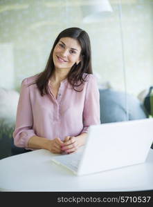 Portrait of confident young businesswoman with laptop at office table