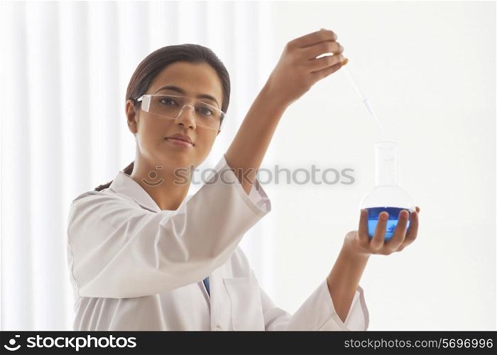Portrait of confident young female scientist experimenting in lab