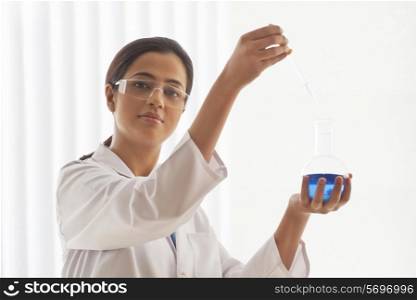 Portrait of confident young female scientist experimenting in lab