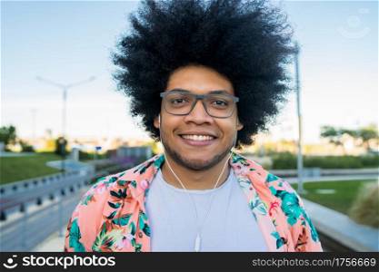 Portrait of confident young latin man smiling and looking at camera while standing outdoors on the street. Urban concept.