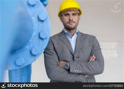 Portrait of confident young male architect standing arms crossed in industry