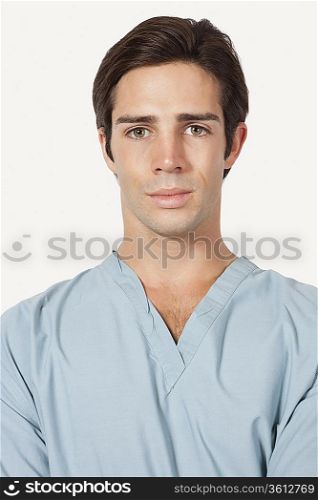 Portrait of confident young man in surgical scrubs over gray background